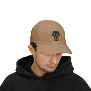 A person wearing a beige cap with a ghost face logo and a black hoodie, showcasing a casual urban style.