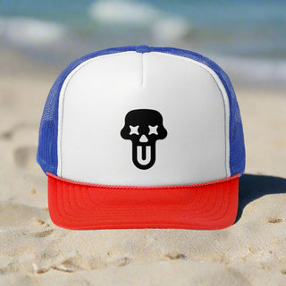 A red and white trucker hat with a blue mesh back, featuring a black ghost face logo with stars for eyes and a tongue sticking out.