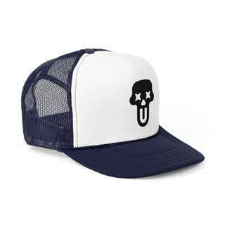A navy blue and white trucker hat featuring a skull graphic with crossed-out eyes and a tongue sticking out — bold graphic design.