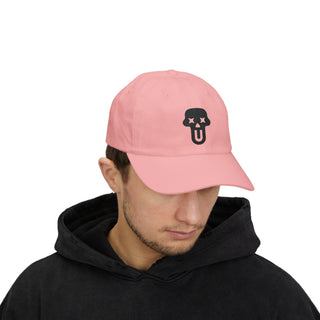 A person wearing a black hoodie and a pink baseball cap featuring a UNFLTRD graphic with crossed eyes and an open mouth.