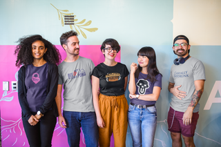 Group of five coworkers wearing matching UNFLTRD graphic t-shirts